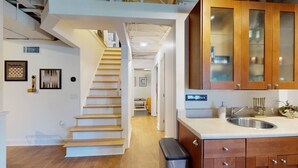 A modern kitchen with wooden cabinets, a stainless steel sink, and a staircase leading to an upper level. - Lake Home with private dock (Gainesville)