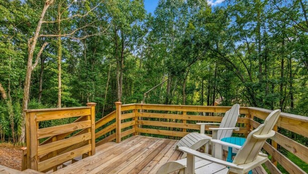 A wooden deck with Adirondack chairs and a table, surrounded by a forest. - Lake Home with private dock (Gainesville)