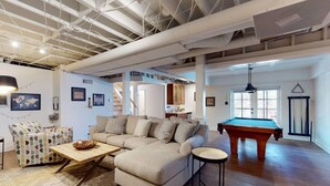 A spacious living room with a pool table, a sofa, and a coffee table. - Lake Home with private dock (Gainesville)