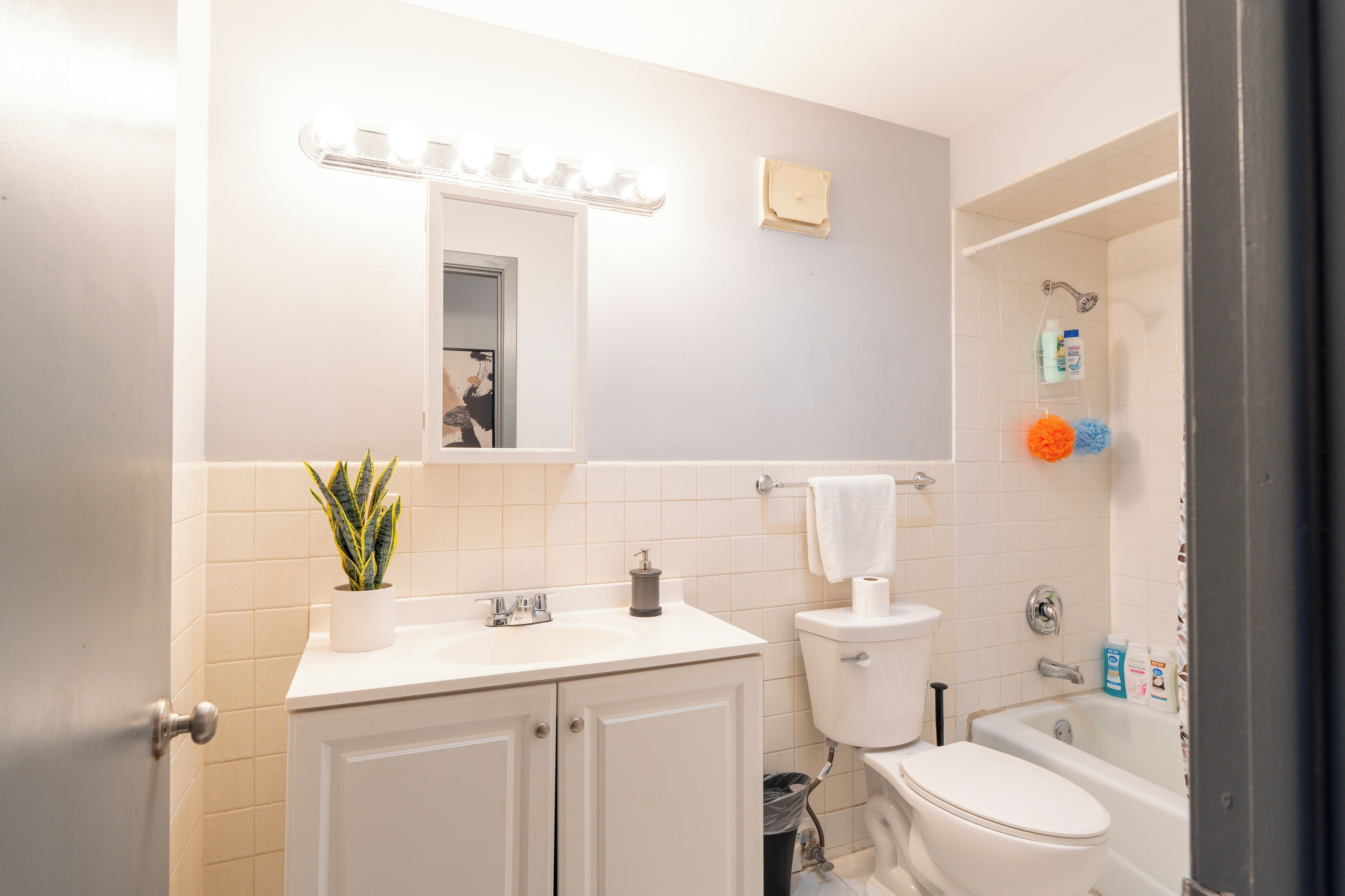 A bathroom with a sink, mirror, toilet, and bathtub.