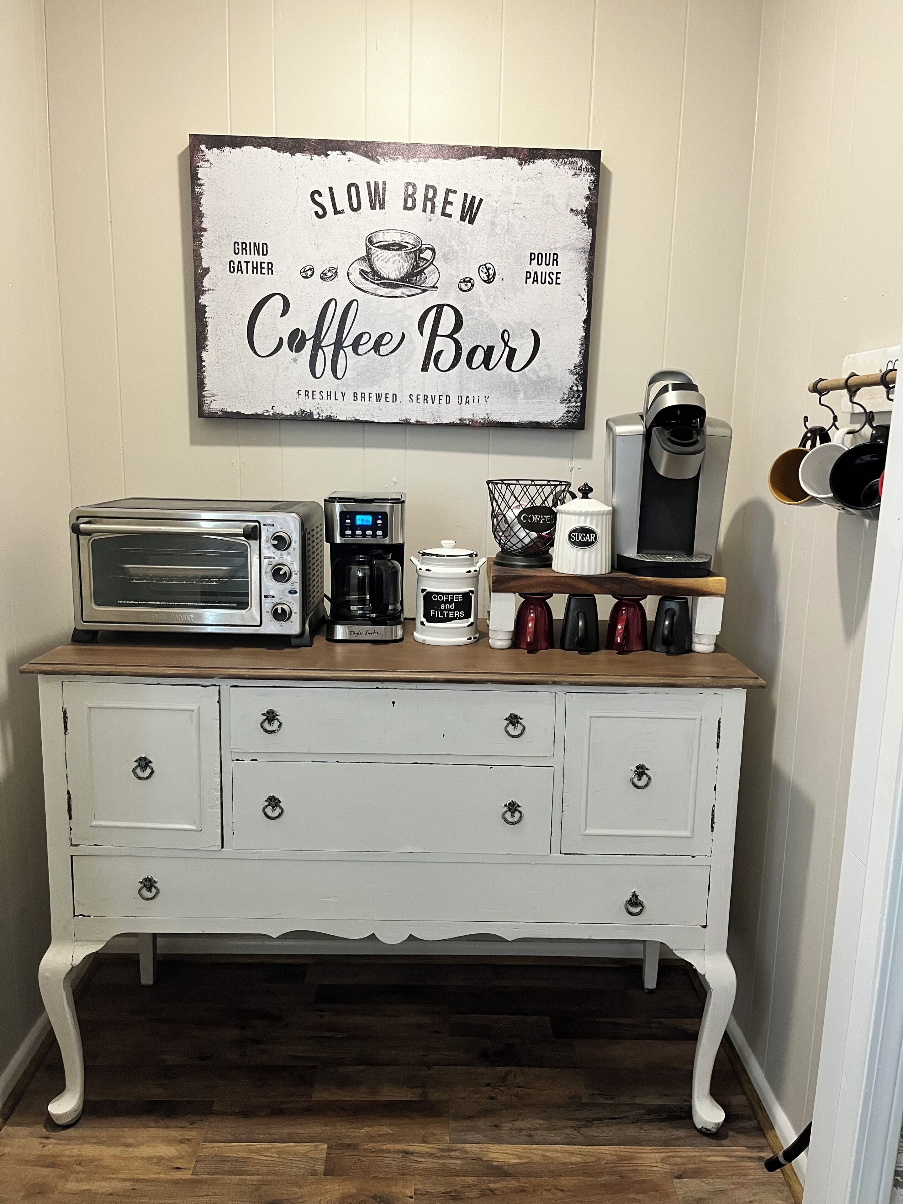Un coin café aménagé avec une enseigne ancienne, un grille-pain, une machine à café et un moulin à café.