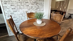 Une table de salle à manger ronde en bois, ornée d’une plante en pot au centre, entourée de chaises en bois.