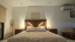 Une chambre à coucher avec un grand lit, deux tables de chevet, un climatiseur fixé au mur et un élément décoratif mural.