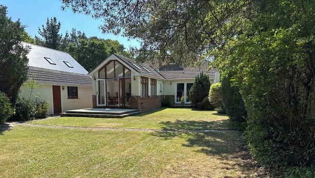Ein zweistöckiges Haus mit Veranda, überdachter Terrasse und gepflegtem Rasen.