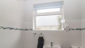 Ein Badezimmer mit Badewanne, Waschbecken, Toilette, Fenster und Spiegel.