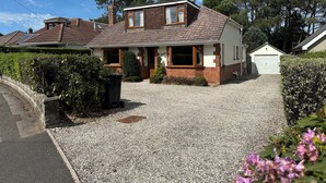 Ein zweigeschossiges Haus mit Schotterauffahrt, Garage und einem gepflegten Garten.