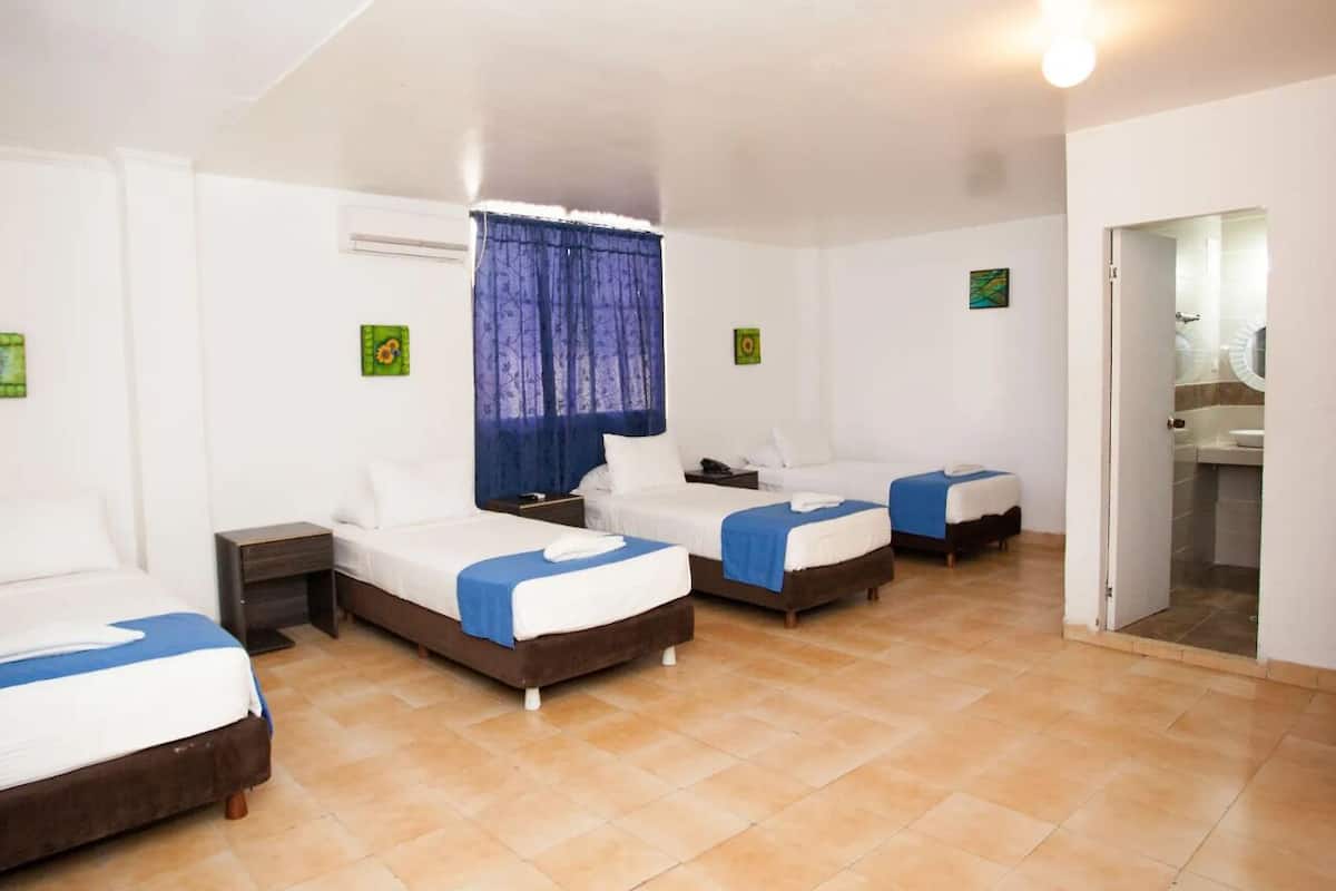 A hotel room with four beds, a bathroom, and a shower.
