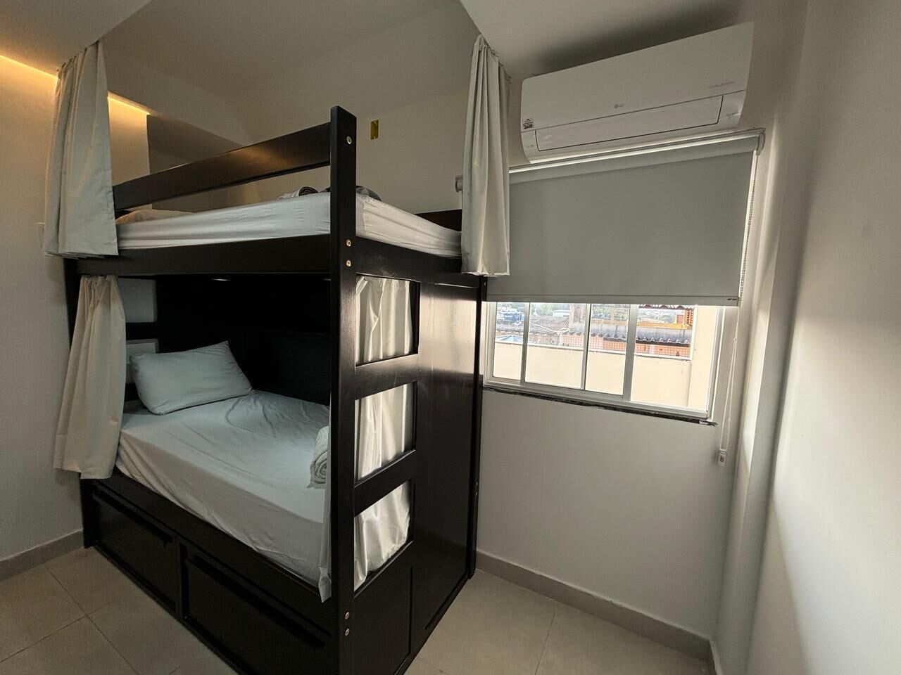 Una litera con cortinas, una ventana con vistas y un equipo de aire acondicionado.