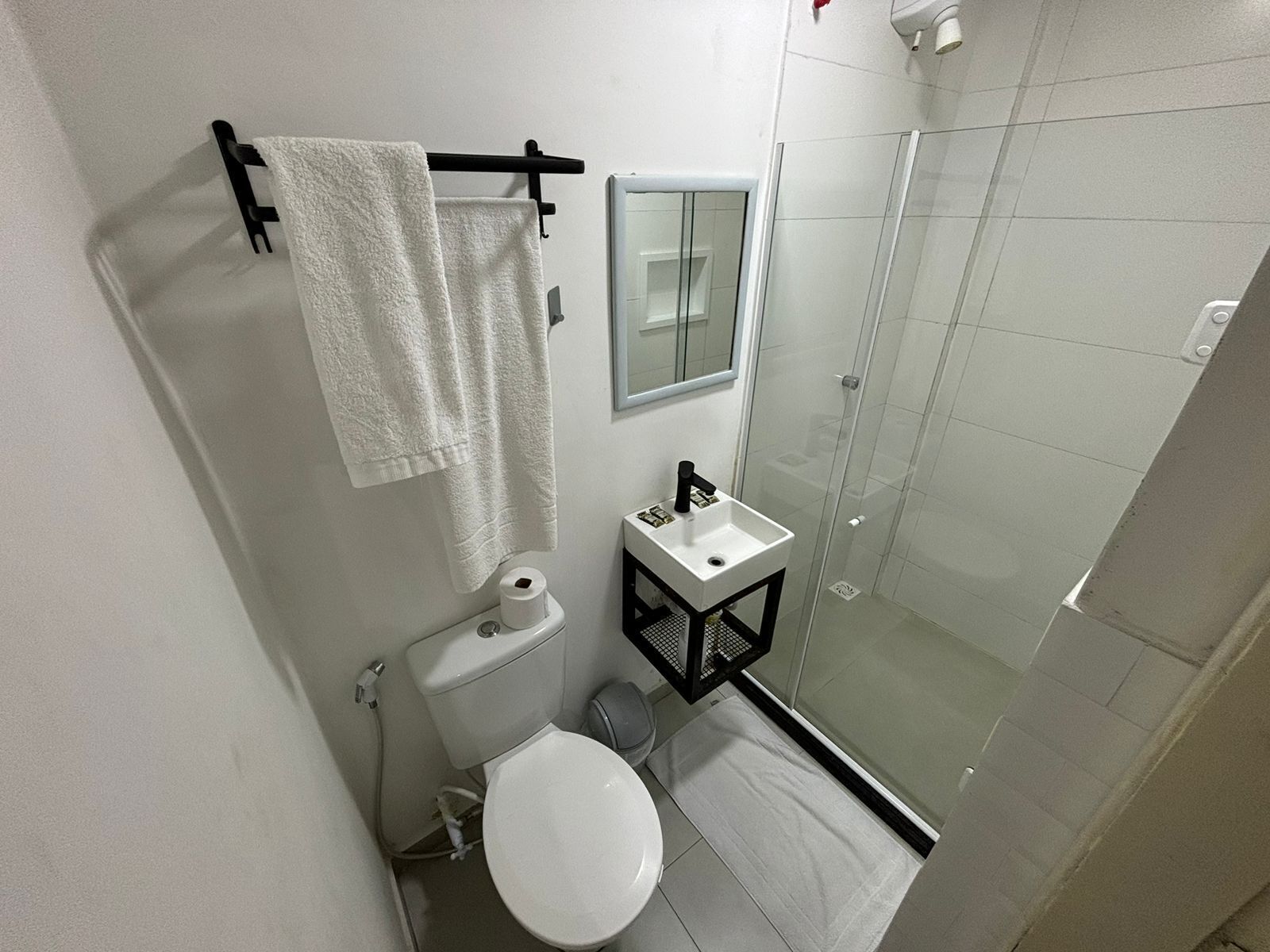 A compact bathroom with a toilet, sink, and glass shower enclosure.
