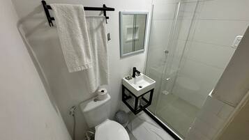 A compact bathroom with a toilet, sink, and glass shower enclosure.