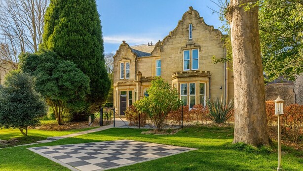 A large, historic building with a checkered lawn in front.