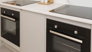 A modern kitchen with a black oven, a white countertop, and a wooden cutting board.