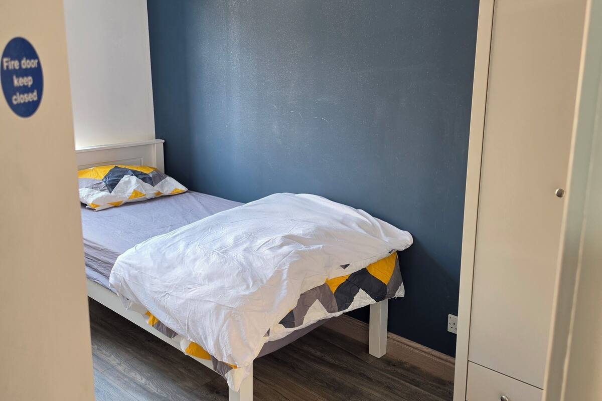 Una camera da letto con un letto, un armadio e una porta con il cartello di sicurezza antincendio.