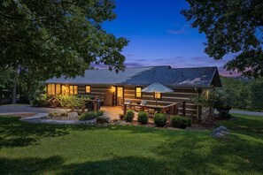 A lodge with a wooden exterior, a covered patio, and a well-maintained lawn.
