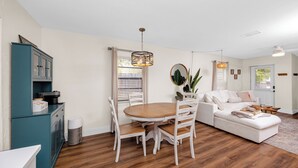 Uma área de jantar com uma mesa e cadeiras de madeira, um sofá branco e um armário verde-água.