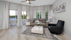 A modern living room with a sofa, coffee table, and a ceiling fan. - Resort Condo 2BR/2BA Minutes to Disney, Pool (Orlando)