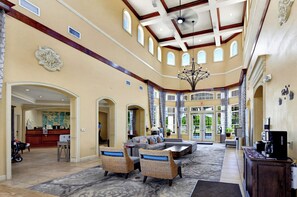 A spacious lobby with a reception desk, seating area, and a chandelier. - Resort Condo 2BR/2BA Minutes to Disney, Pool (Orlando)