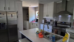 A modern kitchen with stainless steel appliances, a central island, and a view into the adjacent laundry area. - Superb 3-bedroom mobile home with AC in Heathsville (Heathsville)