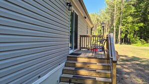 A wooden deck leading to a house with a porch and a chair. - Superb 3-bedroom mobile home with AC in Heathsville (Heathsville)