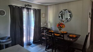 A dining area with a table, chairs, a mirror, and a sign that reads 'gather.' - Superb 3-bedroom mobile home with AC in Heathsville (Heathsville)