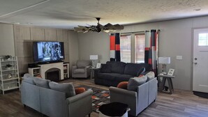 A living room with a television, sofas, a fireplace, and a ceiling fan. - Superb 3-bedroom mobile home with AC in Heathsville (Heathsville)