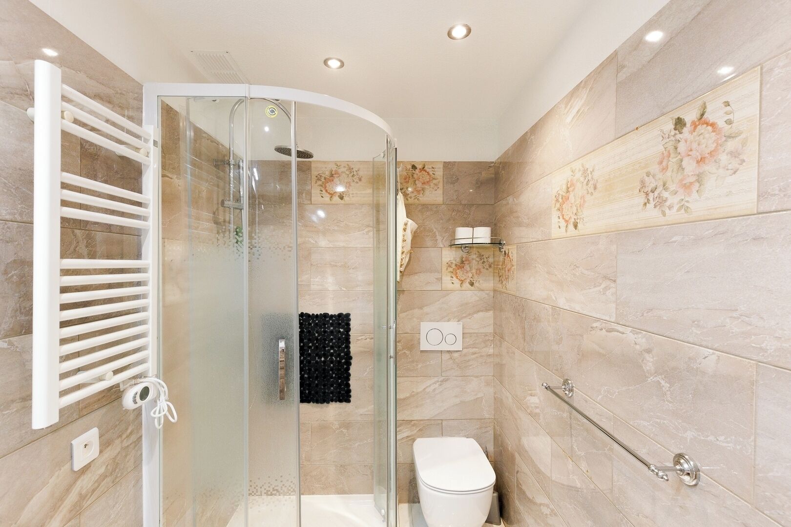 Ein modernes Badezimmer mit Duschkabine aus Glas, Toilette und Handtuchhalterung.