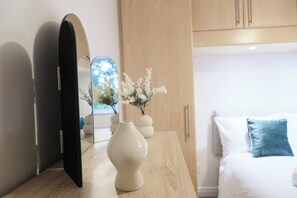 A modern bedroom with a bed, a bedside table with a vase, a mirror, and a wooden wardrobe. - Premium Family and Contractor Free Park | EV Charger (Greater Manchester)