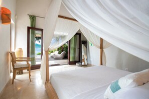 Ein Schlafzimmer mit Bett, einem Sessel und Blick ins Freie.