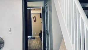 A hallway with a staircase, a chair, and a fire extinguisher. - Wasaga Daze - Unit B (Wasaga Beach)