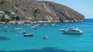 Una zona costera con numerosos barcos y yates anclados en aguas azules y cristalinas.