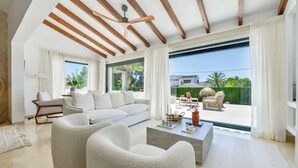Un salón amplio con un sofá grande, una mesa de centro y vistas a un patio con mobiliario exterior.