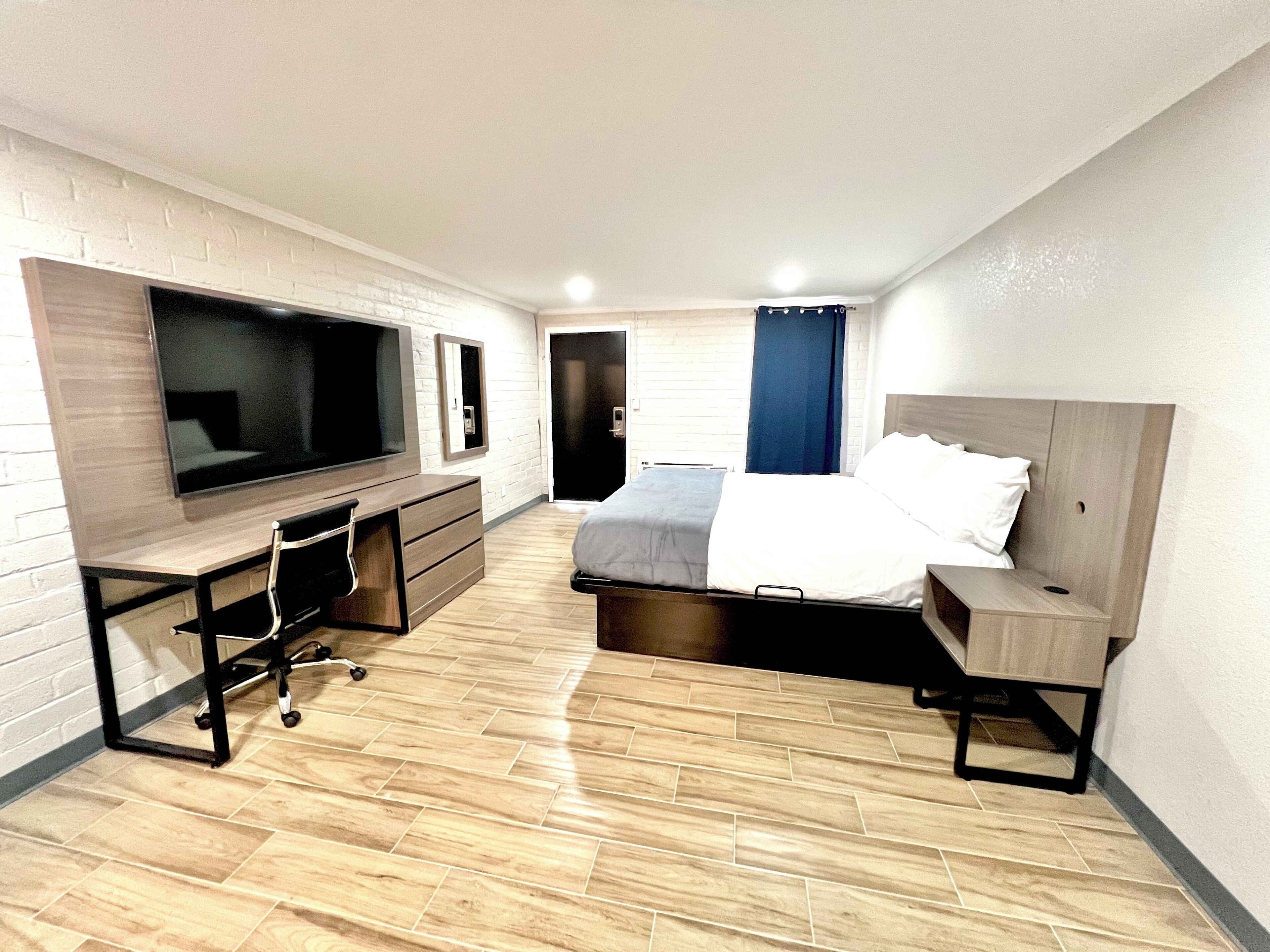 Ein kleines Hotelzimmer mit Bett, Schreibtisch mit Stuhl, Fernseher und Kleiderschrank.