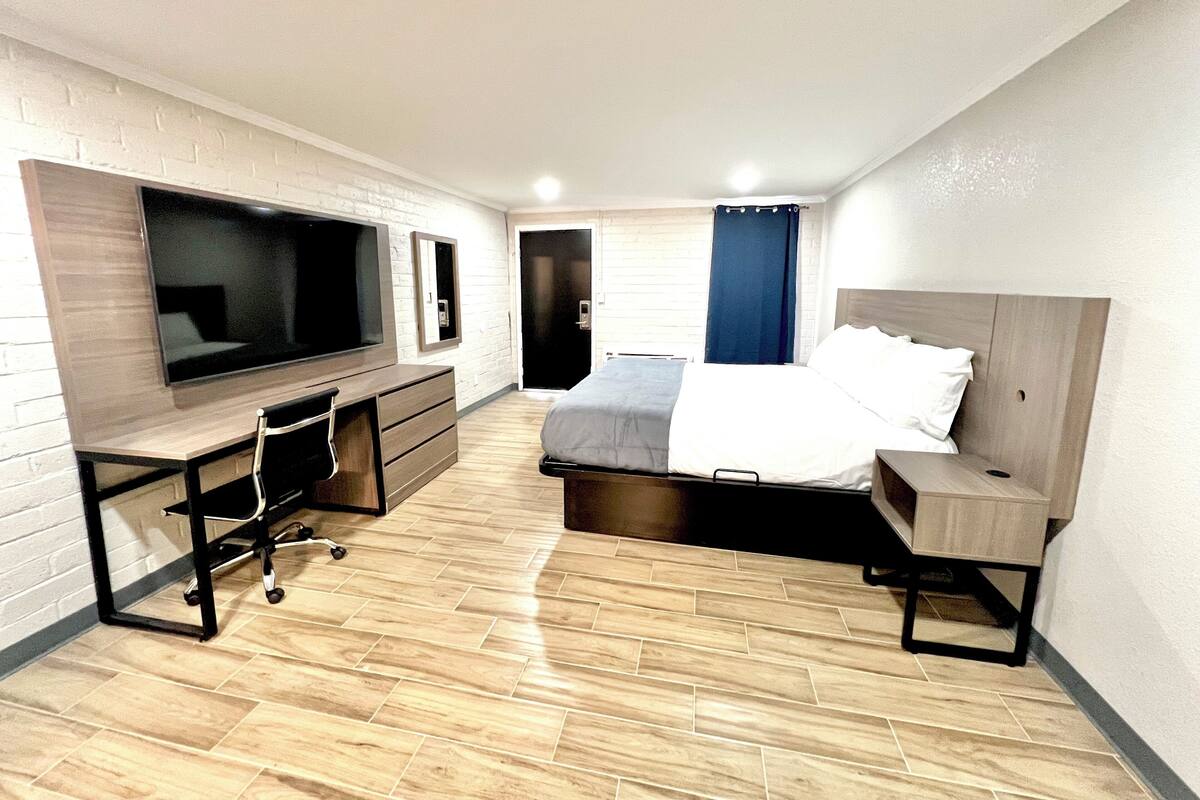 Ein kleines Hotelzimmer mit Bett, Schreibtisch mit Stuhl, Fernseher und Kleiderschrank.