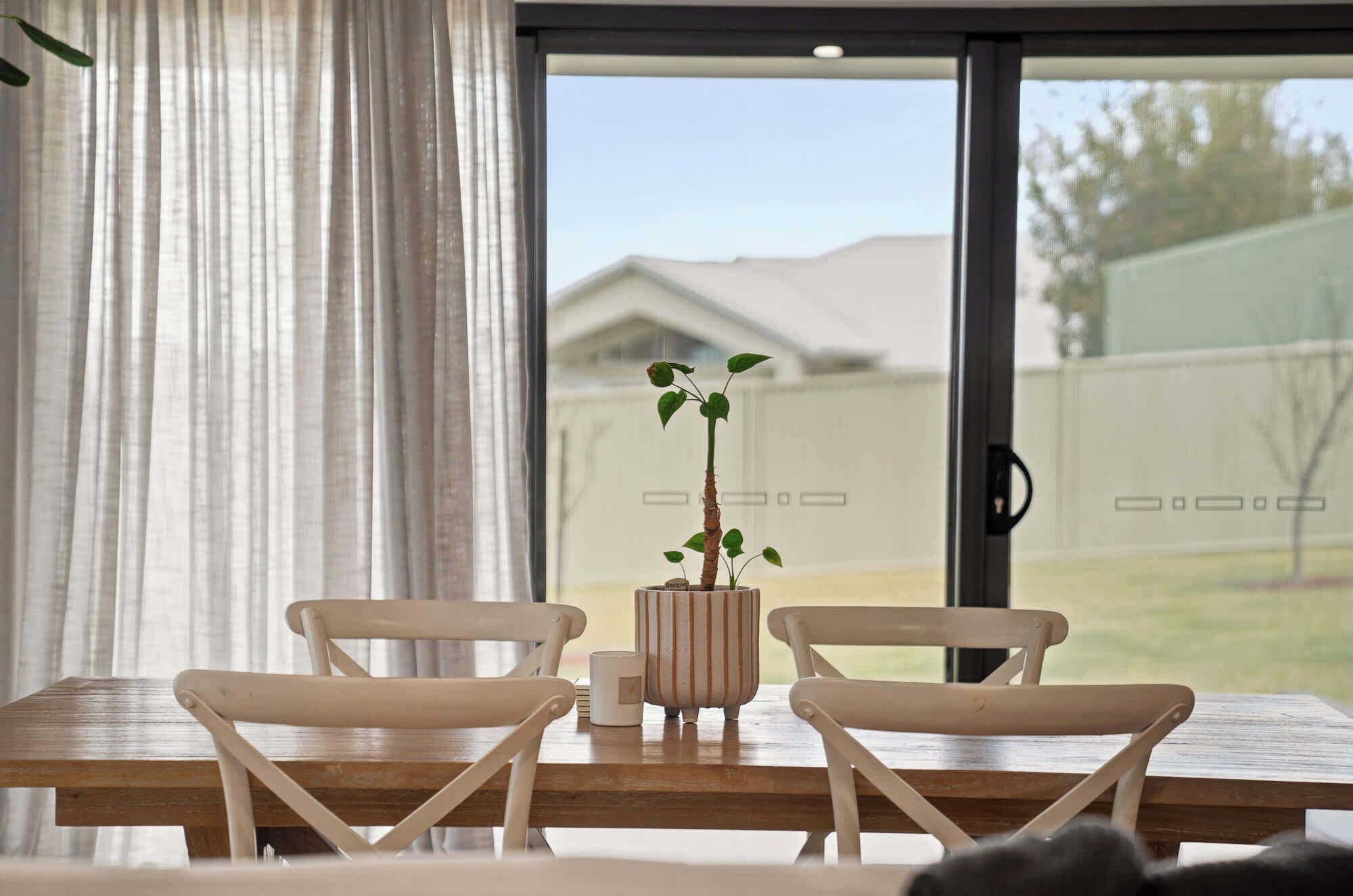 A dining area with a table, chairs, and a potted plant.