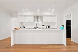 Een moderne keuken met witte kasten, een centraal eiland en hanglampen.