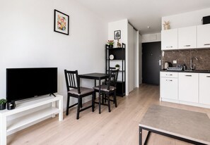 A modern kitchen with white cabinets, a black countertop, and a built-in oven. - Nadolnik Cozy Studio (Poznań)