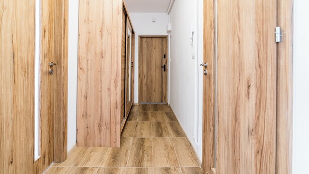 Un couloir avec des portes en bois et un sol carrelé.
