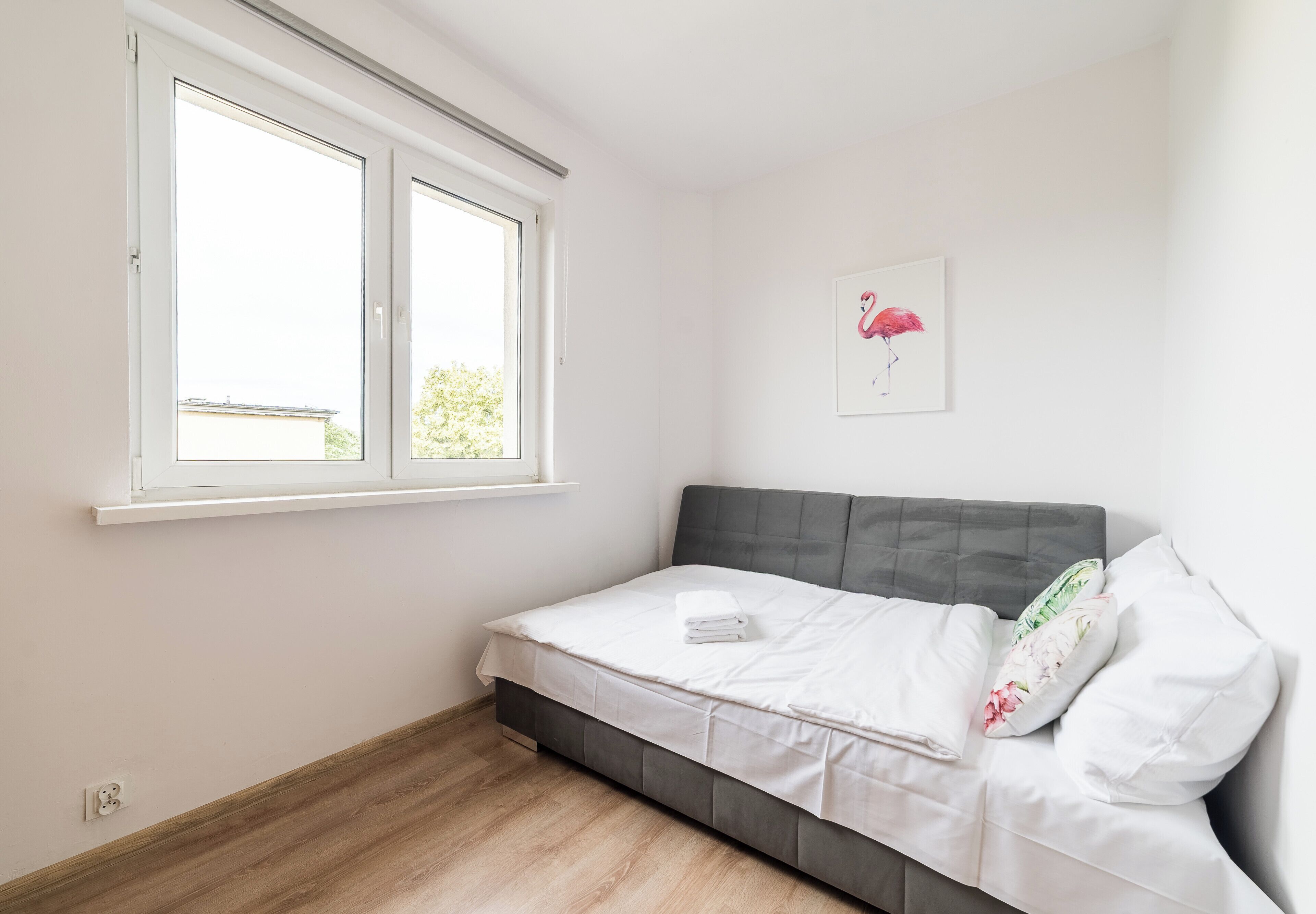 Une chambre à coucher avec un lit, une fenêtre et un tableau accroché au mur.