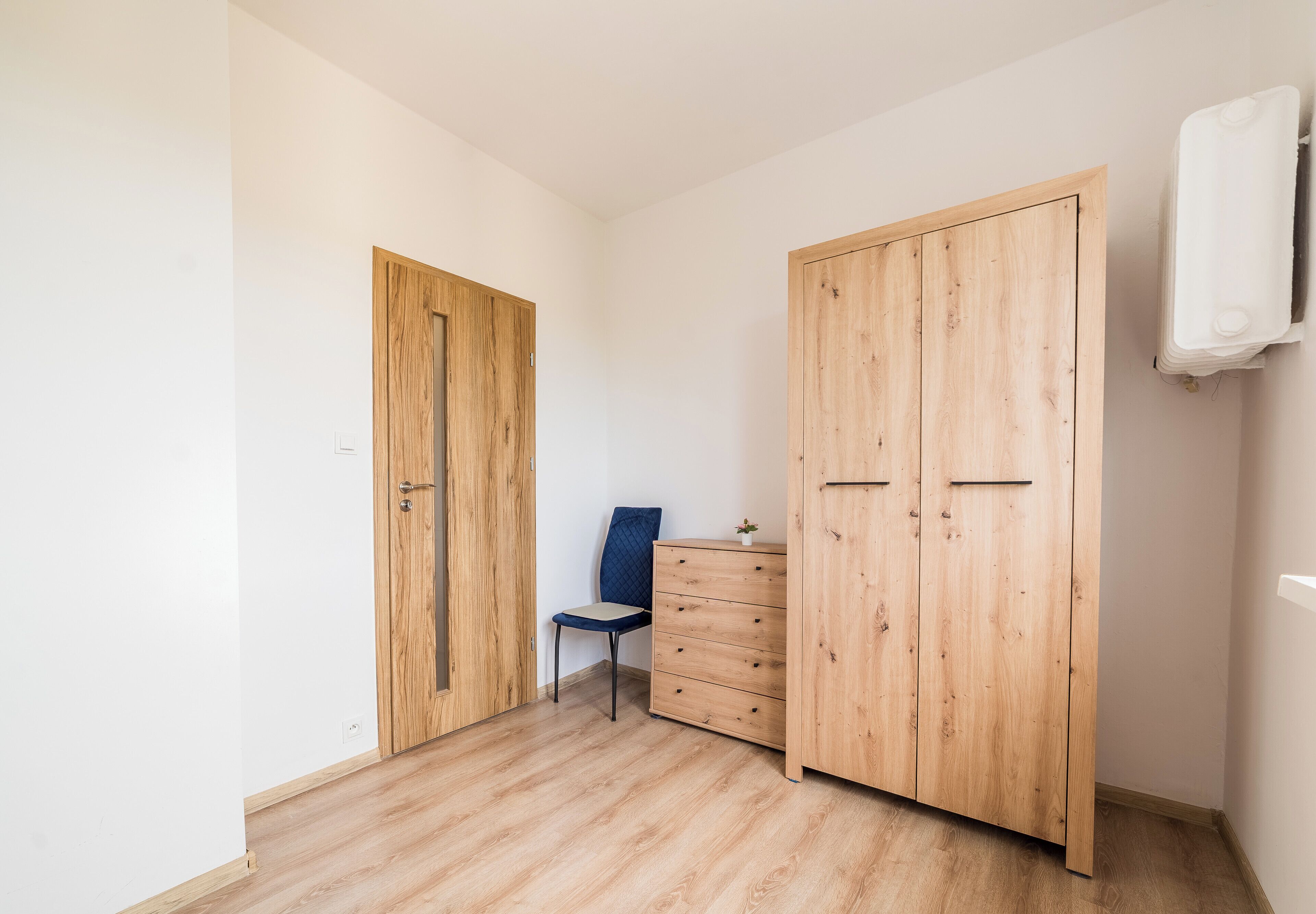Une pièce avec une armoire en bois, une chaise et une petite table.