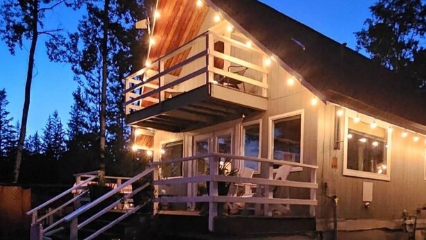 A cabin with a balcony, a wooden deck, and a picnic table.