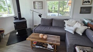 A cozy living room with a fireplace, grey sofa, wooden coffee table, and a ceiling fan.