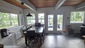 A spacious kitchen with a dining area, large windows, and a wooden ceiling.