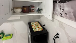A kitchen with a microwave, a toaster, and a red bucket on the counter.