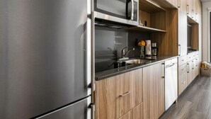 Une cuisine moderne dotée d’appareils électroménagers en acier inoxydable, de meubles en bois et d’un plan de travail noir.