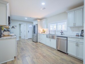 Una cocina moderna con armarios blancos, electrodomésticos de acero inoxidable y suelo de madera.