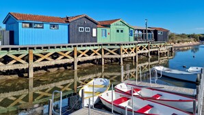 Eine Holzsteganlage mit bunten Gebäuden, vor Anker liegenden Booten und ruhigem Wasser.