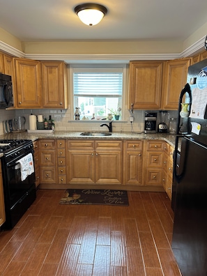 A kitchen with wooden cabinets, a black stove, a sink, and a refrigerator. - 2-bedroom house in fantastic Lower Township back yard and patio (Lower Township)