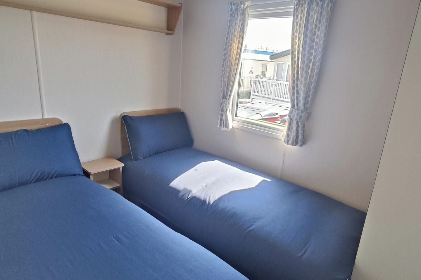 Ein Zimmer mit zwei Betten, einem fensterbelaubten Fenster und Blick nach außen.