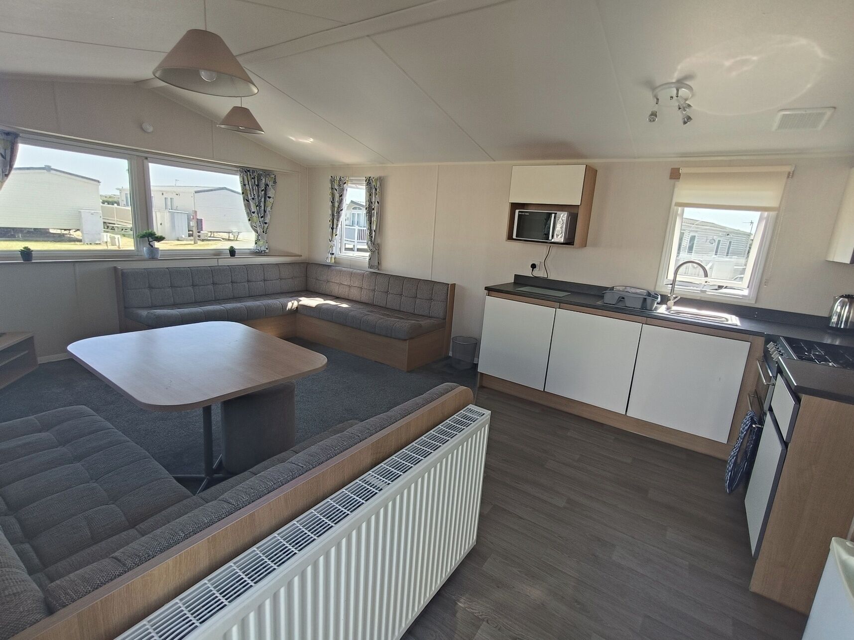 En kompakt bolig i autocamper-stil med et tekøkken, et spiseområde og et opholdsområde med indbygget bænk.