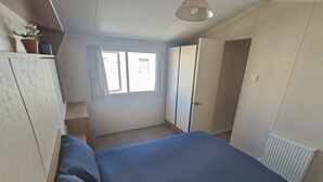 Una camera da letto con un letto, un termosifone, una finestra con tende e una porta.